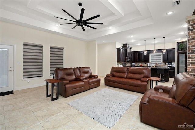 living room with a tray ceiling and ceiling fan