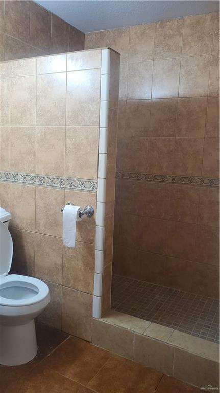 600 N Louisiana Ave N, Weslaco, TX 78596 - full bath with tile patterned floors, a tile shower, and toilet