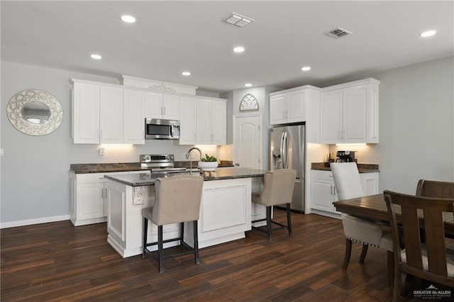 5313 N Crown Pt, Pharr, TX 78577 - kitchen with dark countertops, visible vents, a breakfast bar area, dark wood finished floors, and stainless steel appliances