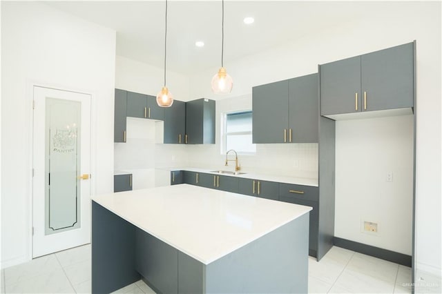 kitchen featuring pendant lighting, a center island, backsplash, sink, and gray cabinets