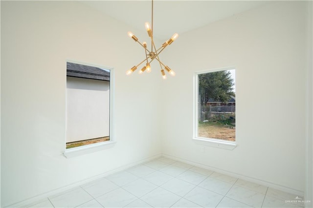 empty room with a chandelier, light tile patterned floors, and vaulted ceiling