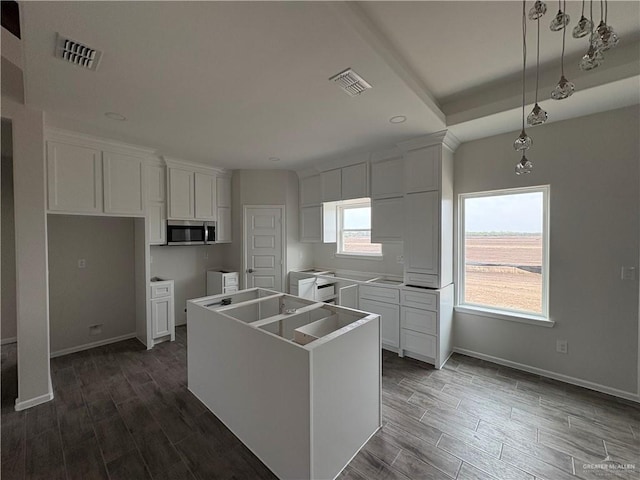 kitchen featuring stainless steel microwave, wood tiled floor, visible vents, and a kitchen island