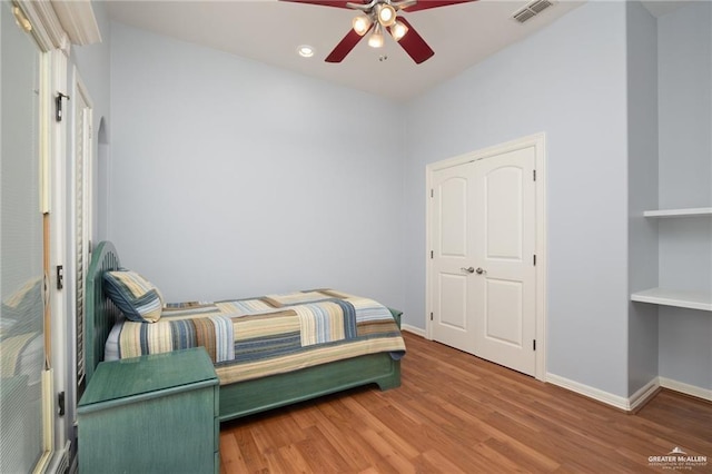 bedroom with baseboards, visible vents, ceiling fan, and wood finished floors