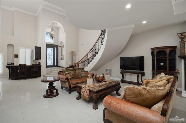 living area featuring visible vents, arched walkways, a high ceiling, stairs, and crown molding