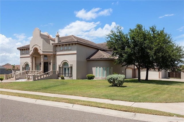 mediterranean / spanish-style home featuring a garage, a tiled roof, a front yard, and stucco siding