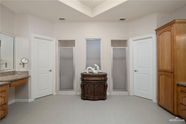 full bathroom featuring a stall shower, baseboards, visible vents, and vanity