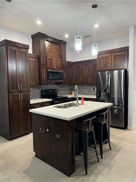 kitchen with sink, tasteful backsplash, decorative light fixtures, a center island with sink, and appliances with stainless steel finishes