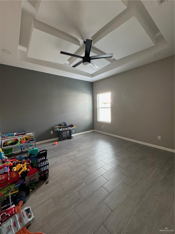 empty room featuring hardwood / wood-style floors, ceiling fan, and a raised ceiling