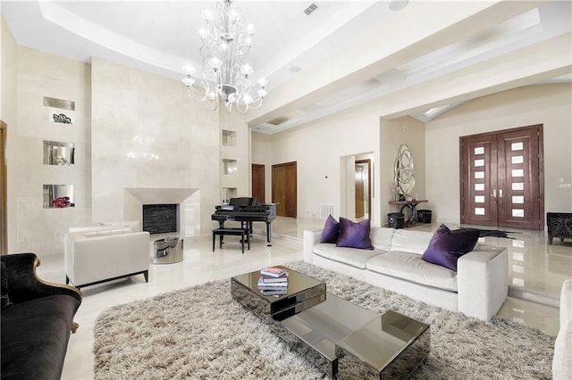 living area featuring a chandelier, visible vents, a raised ceiling, and a high end fireplace