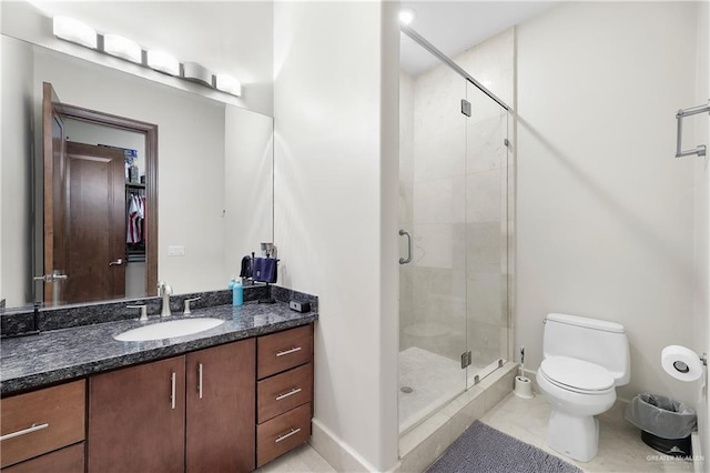 bathroom with toilet, a shower stall, baseboards, and vanity