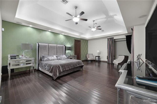 bedroom featuring wood finished floors, a raised ceiling, visible vents, and baseboards