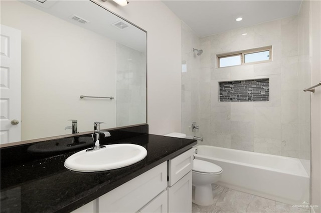 full bathroom with tiled shower / bath, vanity, and toilet