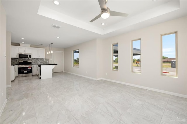 unfurnished living room with sink, ceiling fan, and a tray ceiling