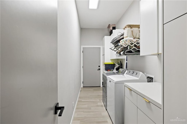 washroom with washer and dryer, cabinets, and light wood-type flooring