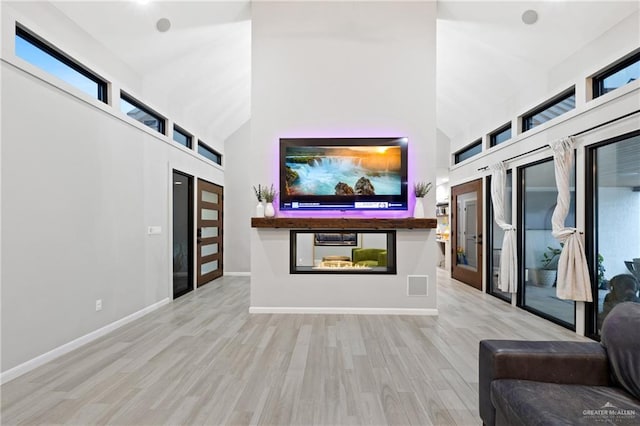 unfurnished living room with french doors, light hardwood / wood-style floors, and high vaulted ceiling