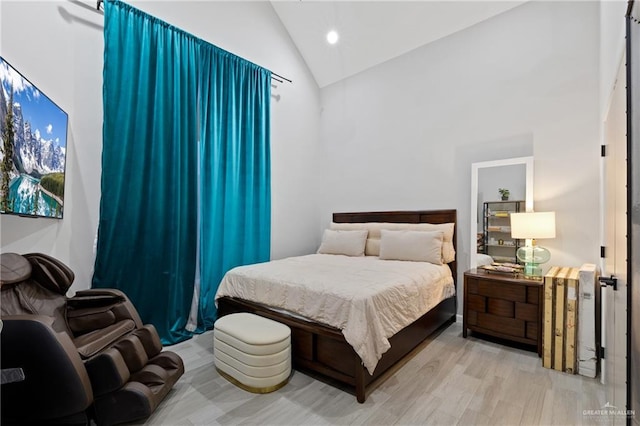 bedroom with light hardwood / wood-style floors and high vaulted ceiling