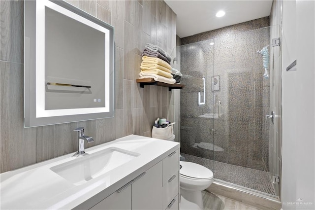 bathroom featuring vanity, toilet, an enclosed shower, and tile walls