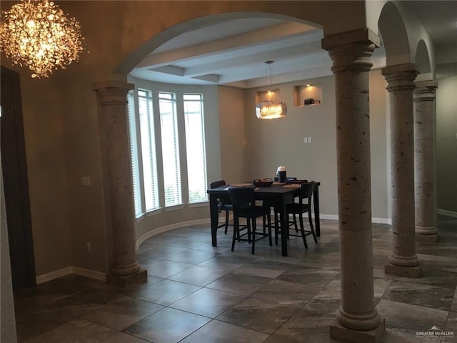 dining area featuring baseboards, arched walkways, a tray ceiling, ornate columns, and a notable chandelier