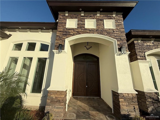 entrance to property featuring stone siding and stucco siding