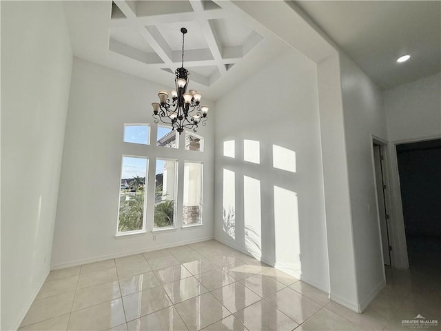 tiled empty room featuring a high ceiling, a chandelier, coffered ceiling, beamed ceiling, and baseboards