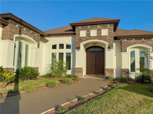 view of exterior entry featuring stone siding and stucco siding