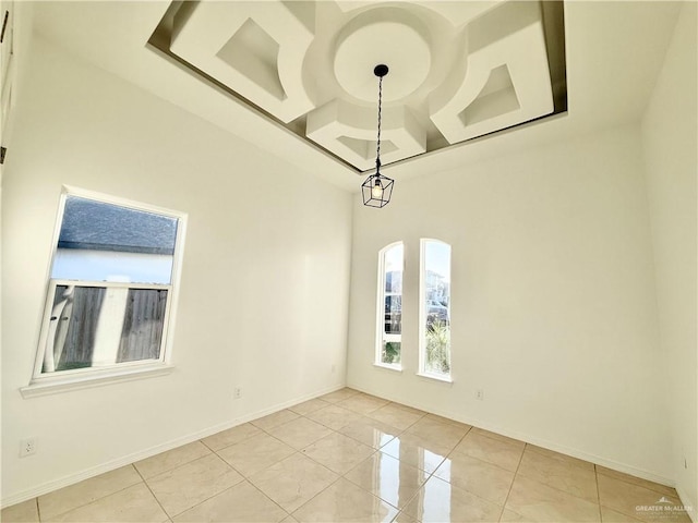 spare room featuring light tile patterned floors, coffered ceiling, and baseboards