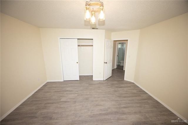 unfurnished bedroom with a closet, hardwood / wood-style floors, and a textured ceiling