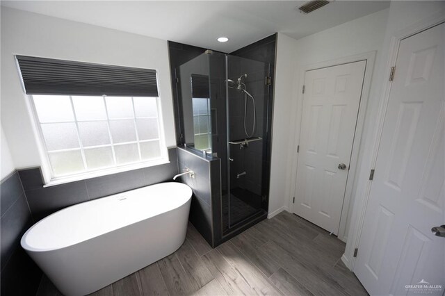 bathroom with hardwood / wood-style flooring, tile walls, and independent shower and bath