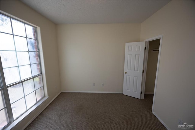 empty room featuring dark carpet and a textured ceiling