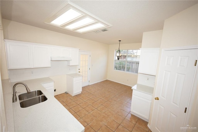 kitchen with light tile patterned flooring, pendant lighting, white cabinetry, and sink