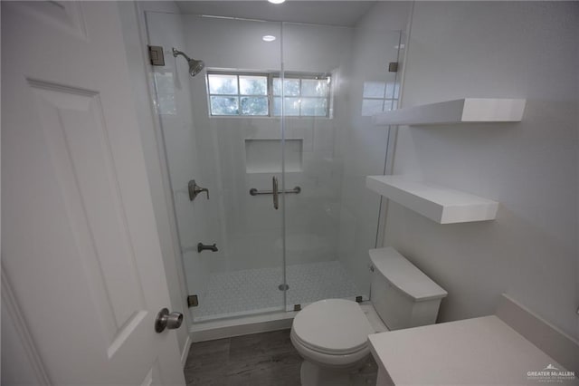 bathroom featuring toilet and a shower with shower door