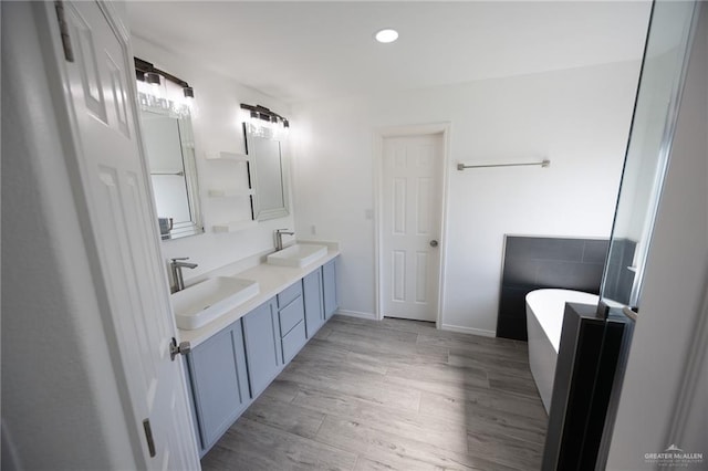 bathroom with vanity, a bath, and wood-type flooring