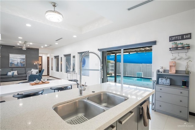 kitchen with a sink, recessed lighting, light stone countertops, open floor plan, and light tile patterned floors
