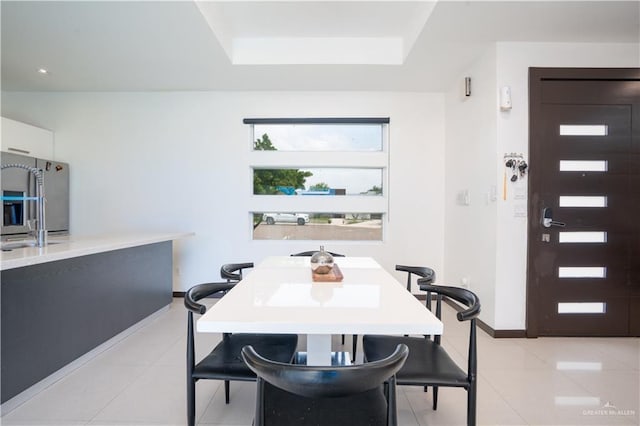 dining area with light tile patterned floors, a tray ceiling, and baseboards