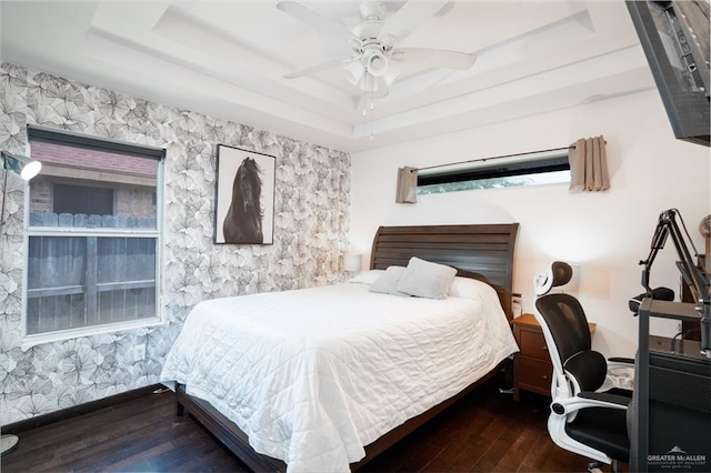 bedroom with a raised ceiling, wood finished floors, and ceiling fan