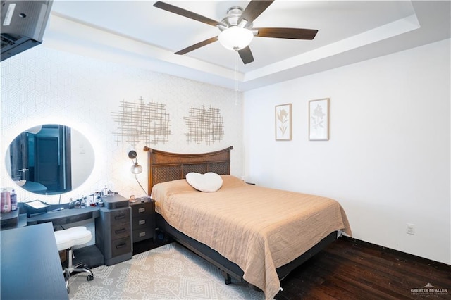 bedroom with wood finished floors, a tray ceiling, and ceiling fan