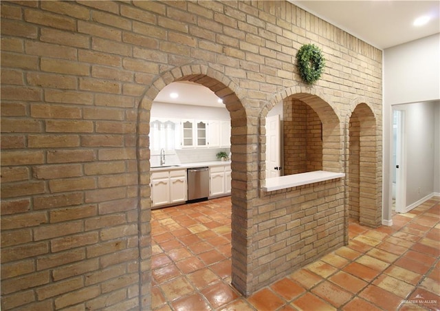 2115 Ichabod Ln, Edinburg, TX 78539 - interior space with dishwasher, white cabinetry, light countertops, glass insert cabinets, and brick wall