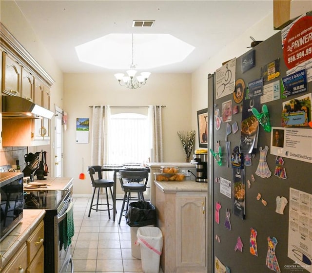 kitchen with appliances with stainless steel finishes, a skylight, light tile patterned floors, pendant lighting, and tile counters