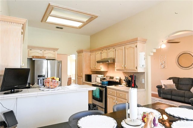 kitchen featuring tile countertops, light brown cabinets, kitchen peninsula, and appliances with stainless steel finishes