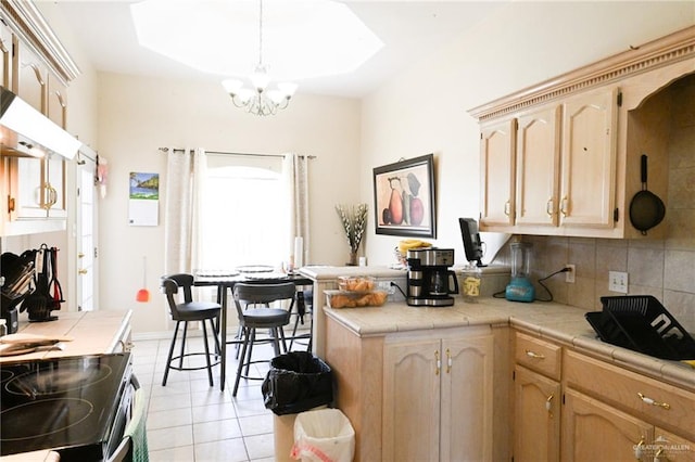 kitchen featuring tile countertops, light brown cabinets, light tile patterned floors, and an inviting chandelier