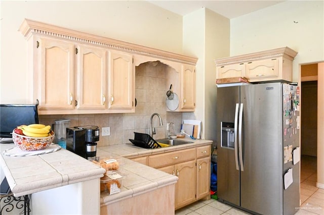 kitchen with kitchen peninsula, stainless steel refrigerator with ice dispenser, backsplash, tile counters, and light tile patterned flooring