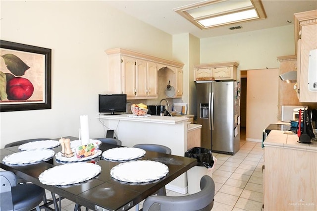 kitchen featuring kitchen peninsula, extractor fan, light tile patterned floors, tile countertops, and stainless steel fridge with ice dispenser