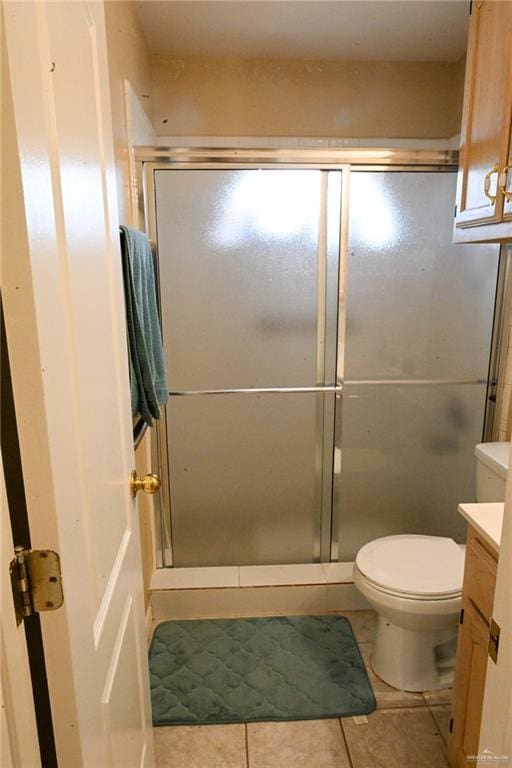 bathroom featuring tile patterned flooring, vanity, toilet, and walk in shower