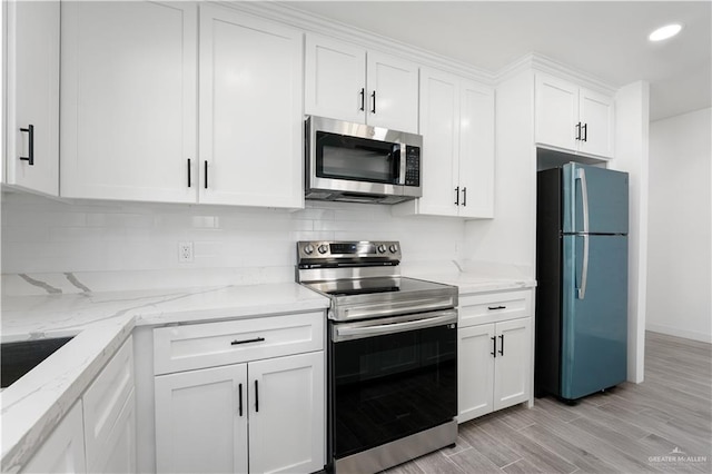 kitchen featuring light stone counters, white cabinetry, stainless steel appliances, and light hardwood / wood-style flooring