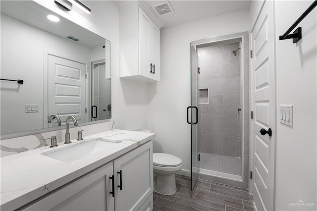 bathroom featuring vanity, toilet, and a shower with shower door