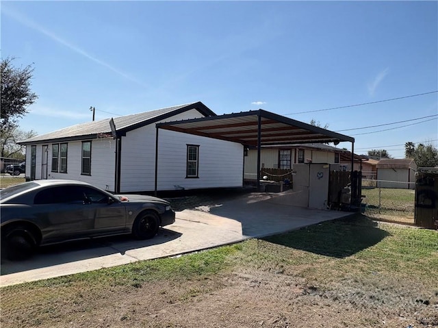 exterior space with dirt driveway, a carport, and fence