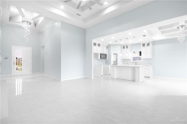 unfurnished living room featuring a raised ceiling, a towering ceiling, and recessed lighting