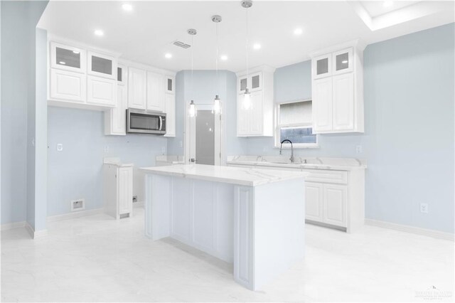 kitchen with white cabinetry, visible vents, stainless steel microwave, and a kitchen island