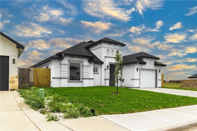 view of front of property with a garage, stucco siding, fence, a front yard, and driveway