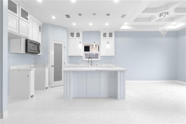 kitchen featuring a center island, a notable chandelier, white cabinetry, stainless steel microwave, and light countertops